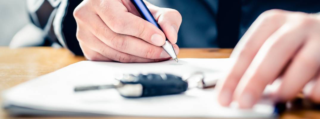 Unknown person signing documents with car key nearby
