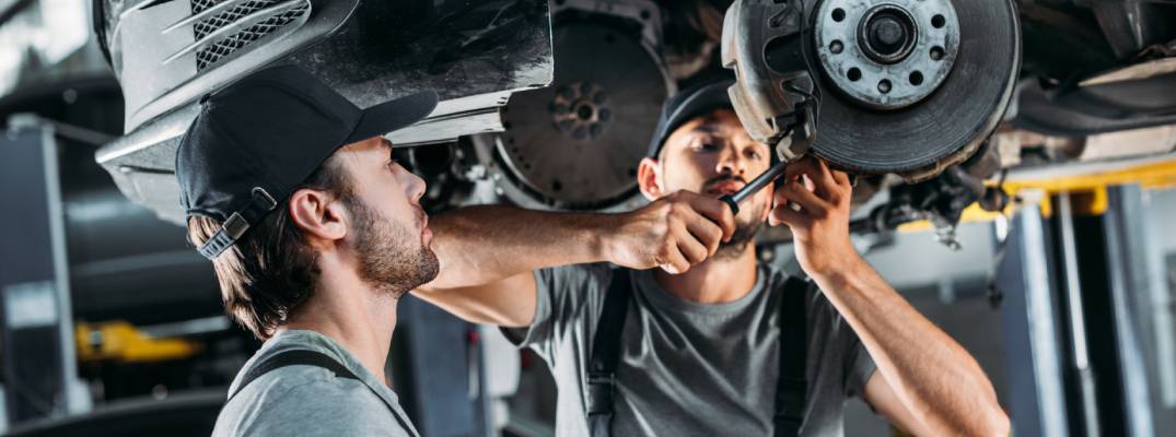 Two mechanics working on vehicle.