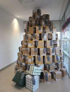 A large pyramid of cardboard boxes stacked in the shape of a Christmas tree inside Kia Victoria, each decorated with pairs of grey socks from the 10,000 Socks Campaign.