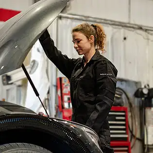 Kia technician looking under hood of vehicle
