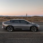 The all-new Kia EV4 parked on the side of a highway with rolling fields and mountains in the distance.