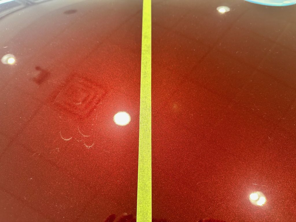 Side-by-side comparison of ceramic coated and uncoated Kia K4 paint in Kia Victoria showroom with visible fingerprints and water spots on uncoated side